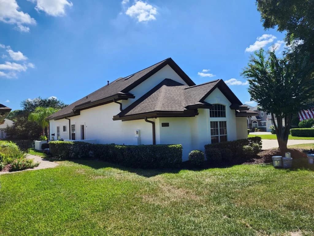 Stucco home with dark trim and neat hedges